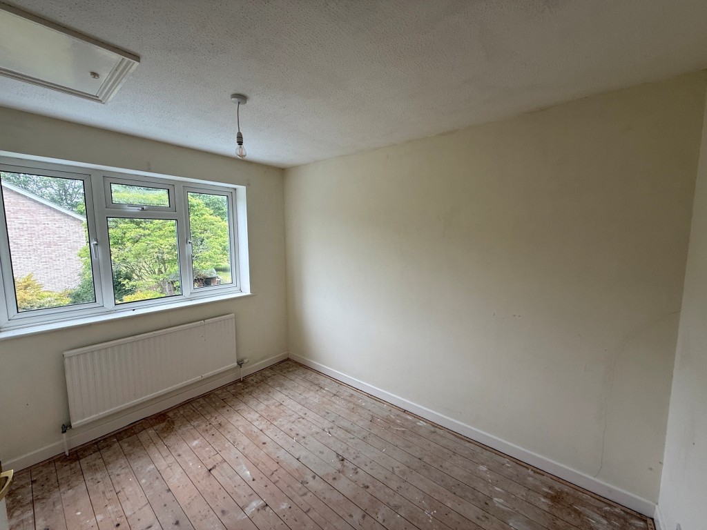 Lot: 114 - THREE-BEDROOM HOUSE FOR IMPROVEMENT AND REPAIR - Bedroom 2 with window overlooking the garden and a loft access